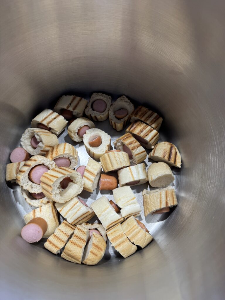 Bierzemy cztery kompletne hot dogi – razem z bułkami i parówkami – i kroimy je na mniejsze kawałki.

Umieszczamy wszystko w garnku i zalewamy wodą.

Następnie podgrzewamy całość i utrzymujemy gorący wywar przez około 60–90 minut. Nie chodzi nam o agresywne smażenie czy przypalanie składników. Chcemy przede wszystkim wypłukać do wody substancje pochodzące z bułki i parówki oraz uzyskać intensywny, charakterystyczny wywar.

Bułka podczas tego procesu praktycznie się rozpada. Parówka oddaje tłuszcz, sól, związki aromatyczne, część białek i innych rozpuszczalnych składników.

